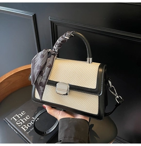 Détail du sac bandoulière tissé bicolore avec foulard en soie et finitions argentées