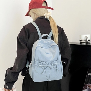 Back view of light blue nylon backpack featuring a cute bow drawstring pocket detail