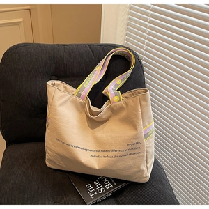 Détail d'un sac cabas en toile kaki avec bandoulière artistique sur un fauteuil
