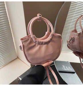 Detail of pink glossy bucket bag with round handle and mirror reflection effect