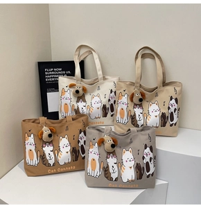 Detail view of large canvas tote bags with cartoon cat prints and plush dog pendants