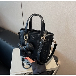 Details der schwarzen Handtasche mit Sternprägung und kleinem Hunde-Anhänger