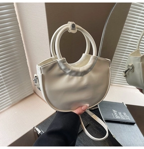 Detail of creamy white crescent handbag with circular handle and detachable shoulder strap