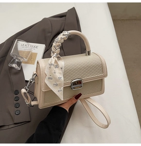 Détail d'un sac à main beige tressé avec poignée foulard en soie et fermoir métallique
