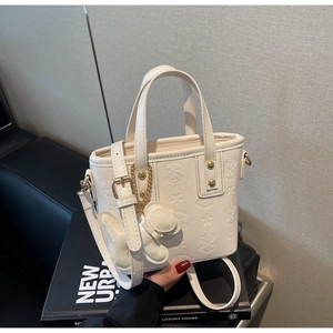 Detail der cremeweißen Mini-Tasche aus Leder mit Sternprägung und Schmetterlingsanhänger