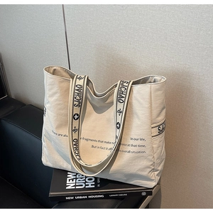 Détail du sac fourre-tout en toile avec bandoulière à logo noir et accessoires minimalistes