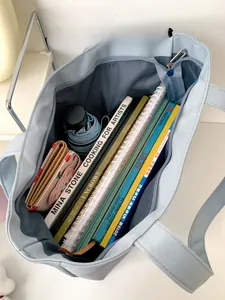 Spacious interior of a light blue canvas tote bag holding books, a wallet, and an umbrella