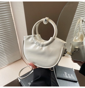 Detail of cream patent leather hobo bag with round handle and adjustable strap
