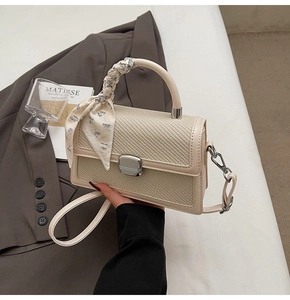 Détail du sac à main en cuir tressé beige avec foulard décoratif et fermoir métallique