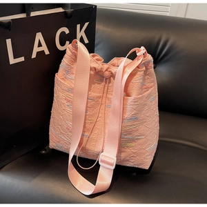 Pink embossed canvas bucket bag featuring colorful embroidery and drawstring closure