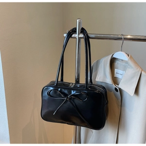 Close-up of glossy black tote bag with bow detail and premium metallic zipper closure