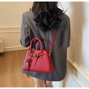Borsa da sposa rossa con ciondolo a cuore indossata su un blazer grigio elegante