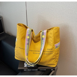 Gros plan du sac fourre-tout jaune vif avec typographie et bandoulière en jacquard
