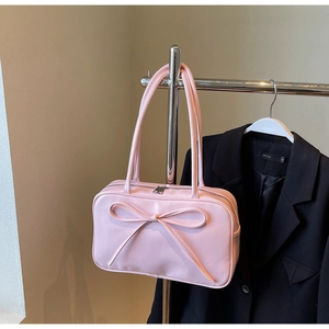 Pink bow shoulder bag with large capacity and smooth faux leather hanging on a metal rack