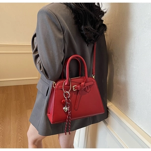 Dettaglio della borsa da sposa rossa con ciondolo a cuore e tracolla in pelle regolabile