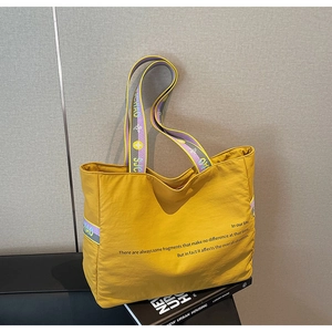 Vue détaillée du cabas en nylon jaune avec anses tissées colorées et imprimé