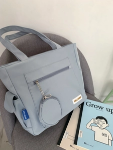 Detail of light blue tote bag featuring side flap pockets and matching mini round charm pouch