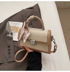 Détail du sac à main texturé avec foulard en soie floral enroulé autour de la poignée