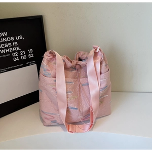 Detail of pink canvas tote bag featuring wavy colorful embroidery and wide nylon strap
