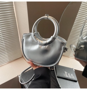 Close-up of a silver crescent-shaped leather handbag with metallic finish and round handle