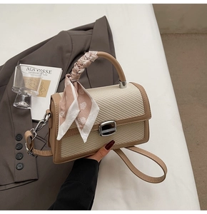 Détail du sac tissé bicolore avec foulard à motifs cœurs et fermoir métallique argenté