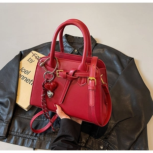 Dettaglio borsa da sposa rossa con ciondolo a cuore e hardware dorato su pelle nera