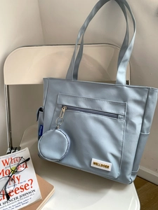 Close-up of a light blue large capacity tote bag with a matching coin purse on a chair
