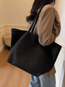 Black canvas tote bag with embossed lettering for women in minimalist interior