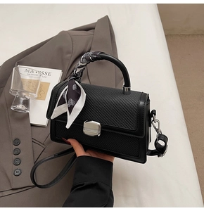 Vue détaillée du sac à main noir tressé avec fermoir argenté et foulard en soie décoratif