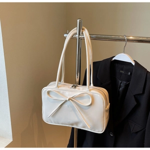 Detail of white leather shoulder bag with decorative bow and silver zipper closure