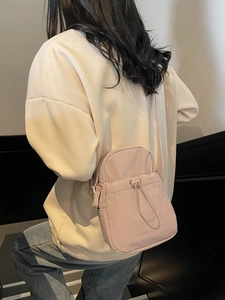 Minimalist light pink drawstring crossbody phone bag for women shown on model