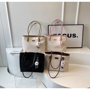 Detailed view of four textured tote bags with plush charms on a minimalist display