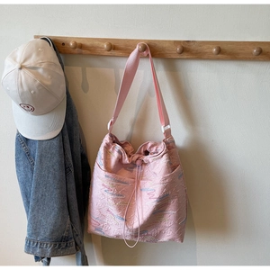 Pink canvas bucket bag detail with textured monogram and drawstring closure on hook