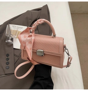 Détail du sac bandoulière rose tressé avec fermoir argenté et foulard en soie à cœurs