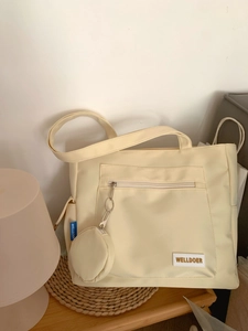 Detail of beige tote bag featuring detachable round coin purse and brand logo tag