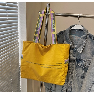 Détails du cabas en toile jaune avec sangles latérales réglables et poignées contrastées