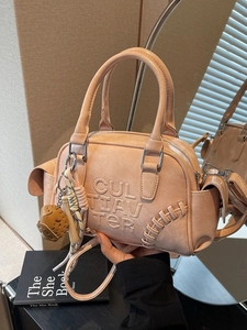 Pink baseball-themed tote bag with embossed text and bat charm accessory shown in use