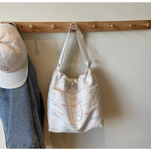 Detail of white canvas bucket bag with textured fabric, drawstring and side pocket