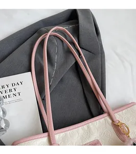Detail of floral embossed tote bag with smooth pink shoulder straps and metal rings