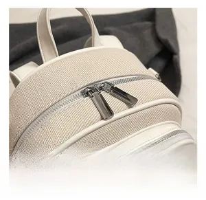 Detailed macro view of silver dual zippers and woven texture on a white backpack