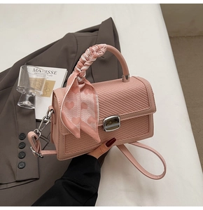 Détail du sac en cuir tressé rose avec poignée en foulard et fermoir rotatif argenté