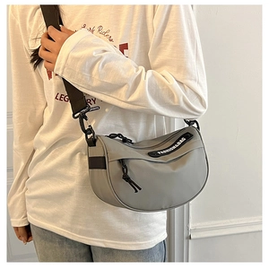 Detail view of grey nylon crescent saddle bag with fashion brand logo and adjustable strap