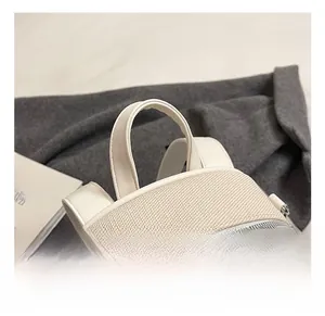 Detail of beige canvas and leather backpack showing the top handle and metal zippers