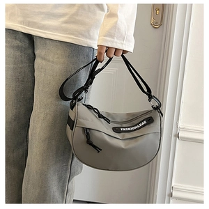 Detail of grey nylon crescent bag with wide adjustable strap and branded label