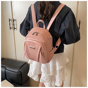 Detail eines rosa Canvas-Rucksacks mit mehreren Reißverschlussfächern und Logo-Schild