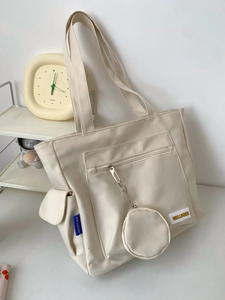 Detail view of cream tote bag with multiple pockets and small coin purse attachment