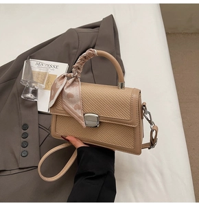 Détail du sac tissé marron clair avec fermoir argenté et foulard en soie à cœurs roses