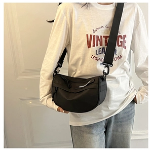 Close-up of black nylon crescent saddle bag with wide strap and fashion logo tag