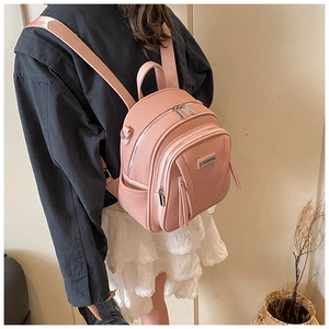 Side view of a pink textured leather mini backpack with adjustable fabric straps on a model