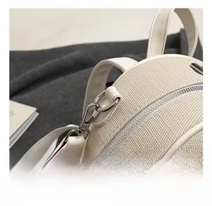 Detail showing high-quality silver metal hook and woven strap on white fabric backpack
